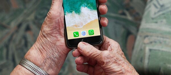 Un teléfono móvil en manos de una persona mayor  - Sputnik Mundo