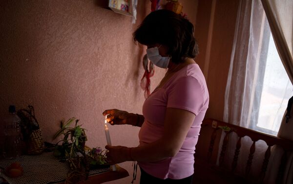  Marta Jaque enciende una vela a los santos en su altar casero durante el domingo de pascua. Quito, Ecuador.  - Sputnik Mundo