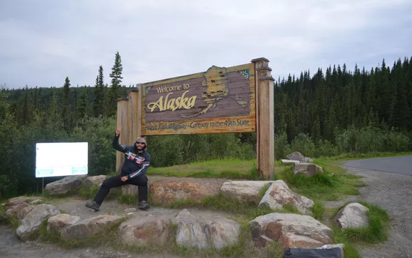 El MotoNauta en Alcan, en el cartel de bienvenida que está al salir de los territorios del norte de Canadá y entrar a Alaska, en la frontera con Yukon El MotoNauta en Alcan, en el cartel de bienvenida que está al salir de los territorios del norte de Canadá y entrar a Alaska, en la frontera con Yukon - Sputnik Mundo