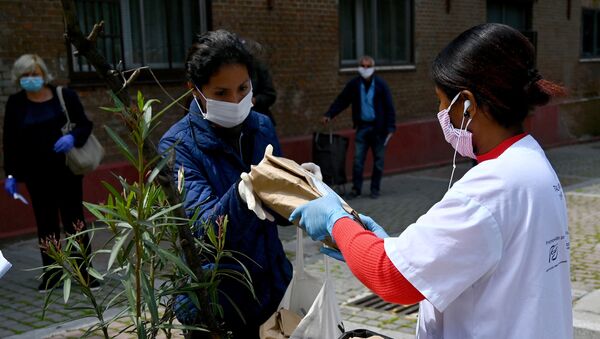 Mujer recibiendo una bolsa de alimentos en el barrio de Puente de Vallecas (Madrid) - Sputnik Mundo