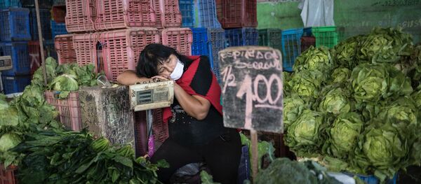 Kathy Velázquez, usando una mascarilla protectora como precaución contra el coronavirus, toma una siesta en su puesto de verduras mientras espera a los clientes en Lima. - Sputnik Mundo
