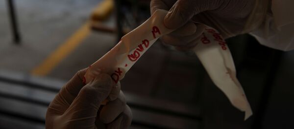 Un trabajador de una funeraria sostiene la cinta que dice COVID-19 - Sputnik Mundo