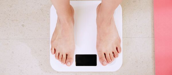 Una persona sobre una báscula - Sputnik Mundo