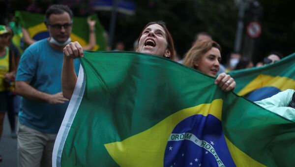 Una mujer sostiene la bandera de Brasil en una manifestación en Río de Janeiro Una mujer sostiene la bandera de Brasil en una manifestación en Río de Janeiro - Sputnik Mundo