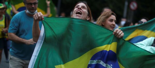 Una mujer sostiene la bandera de Brasil en una manifestación en Río de Janeiro - Sputnik Mundo