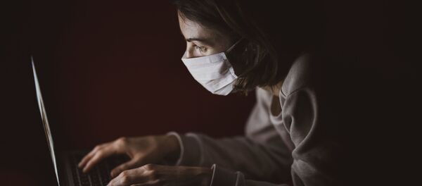 Una persona con mascarilla mirando la pantalla - Sputnik Mundo