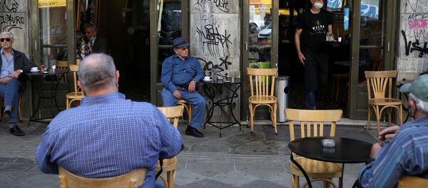 Un camarero sirve a los clientes de una cafetería el día que los restaurantes vuelven a abrir en Atenas tras el 'lockdown' por el COVID-19 - Sputnik Mundo