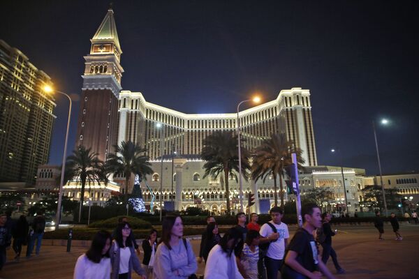 People walk across a road in front of the Venetian Macao casino resorts in Macau People walk across a road in front of the Venetian Macao casino resorts in Macau - Sputnik Mundo