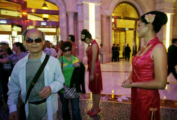 Mainland Chinese visitors walk past attendants at the Galaxy Macau in Macau. Mainland Chinese visitors walk past attendants at the Galaxy Macau in Macau. - Sputnik Mundo