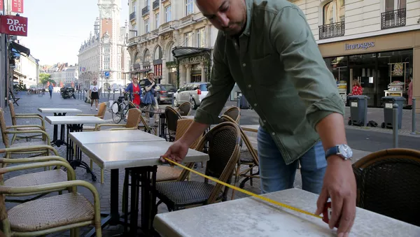 Un hombre toma medidas para asegurar el distanciamiento físico en un bar