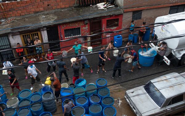 La gente llena los envases plásticos con agua en Petare, Caracas - Sputnik Mundo