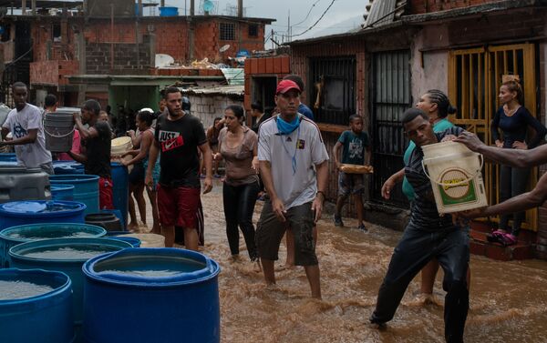 La gente llena los envases plásticos con agua en Petare, Caracas - Sputnik Mundo