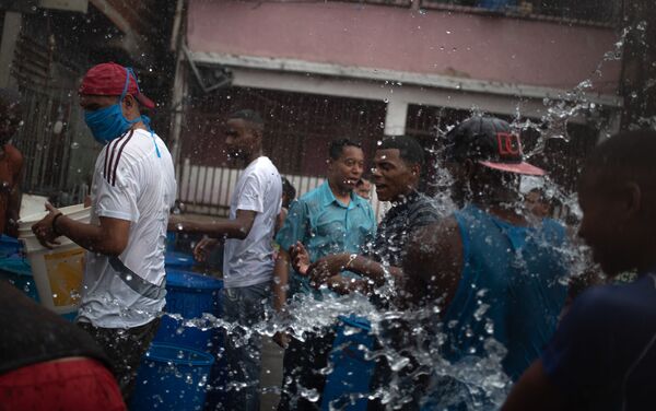 La gente llena los envases plásticos con agua en Petare, Caracas - Sputnik Mundo