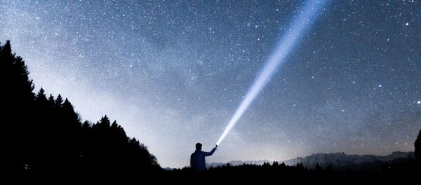 Una persona sostiene una linterna hacia el cielo - Sputnik Mundo