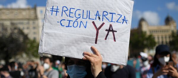 Un hombre sostiene una pancarta durante la manifestación por los migrantes en Barcelona - Sputnik Mundo