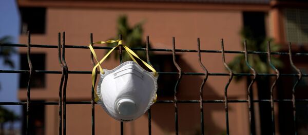 Una mascarilla colgada en una cerca Una mascarilla colgada en una cerca - Sputnik Mundo
