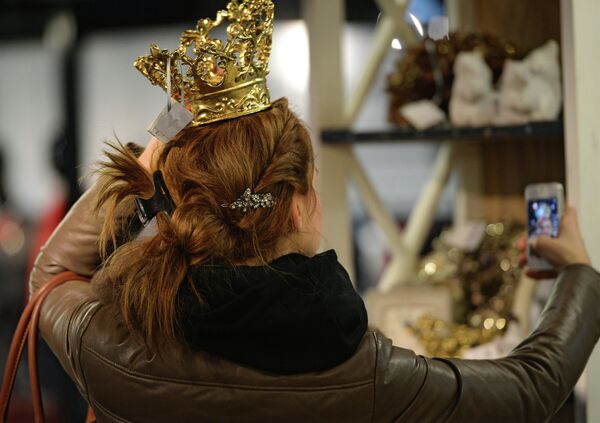 Una mujer se hace una foto con la corona navideña Una mujer se hace una foto con la corona navideña - Sputnik Mundo