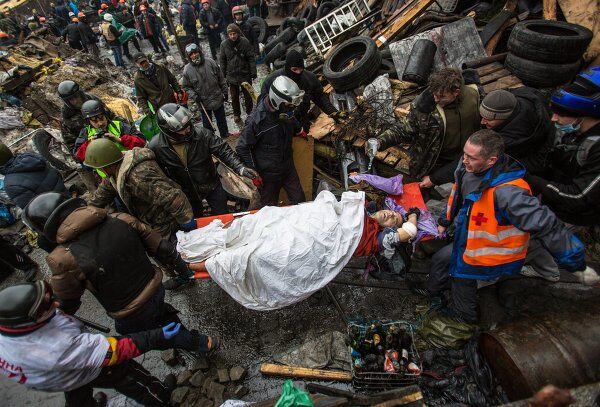 Protesters carry an injured comrade during a clash with riot police in Kiev Protesters carry an injured comrade during a clash with riot police in Kiev - Sputnik Mundo