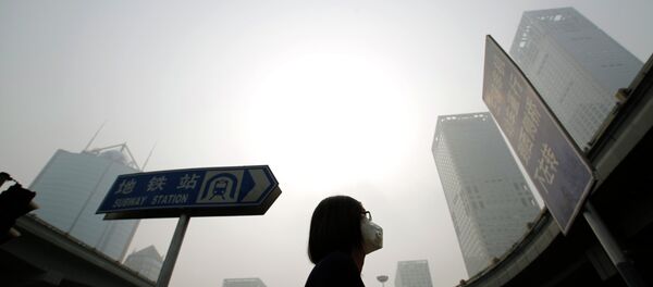 A woman wearing a mask makes her way on a street amid heavy haze and smog in Beijing, in this October 11, 2014 - Sputnik Mundo