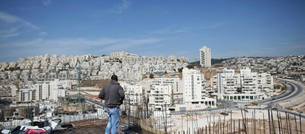 A labourer stands on an apartment building under construction in a Jewish settlement known to Israelis as Har Homa and to Palestinians as Jabal Abu Ghneim, in an area of the West Bank that Israel captured in a 1967 war and annexed to the city of Jerusalem, October 28, 2014. - Sputnik Mundo