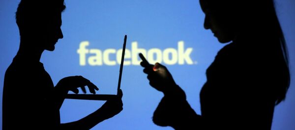 People are silhouetted as they pose with laptops in front of a screen projected with a Facebook logo, in this picture illustration taken in Zenica October 29, 2014. - Sputnik Mundo