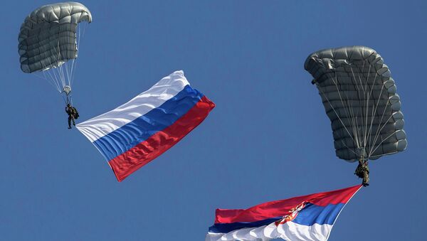 Serbian paratroopers descend to the ground holding Serbian and Russian (L) national flags during a training exercise in the village of Nikinci, west from Belgrade, November 14, 2014. - Sputnik Mundo