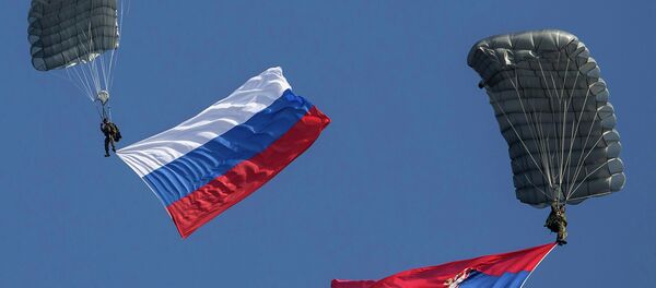 Serbian paratroopers descend to the ground holding Serbian and Russian (L) national flags during a training exercise in the village of Nikinci, west from Belgrade, November 14, 2014. - Sputnik Mundo